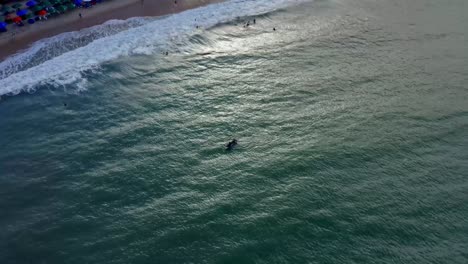 circling aerial drone shot of kayakers paddling near the coastline of the beach praia do madeiro near pipa in northeastern brazil on a warm summer day