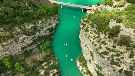 kayaks and boats float on the turquoise waters of gorges du verdon canyon surrounded by steep cliffs