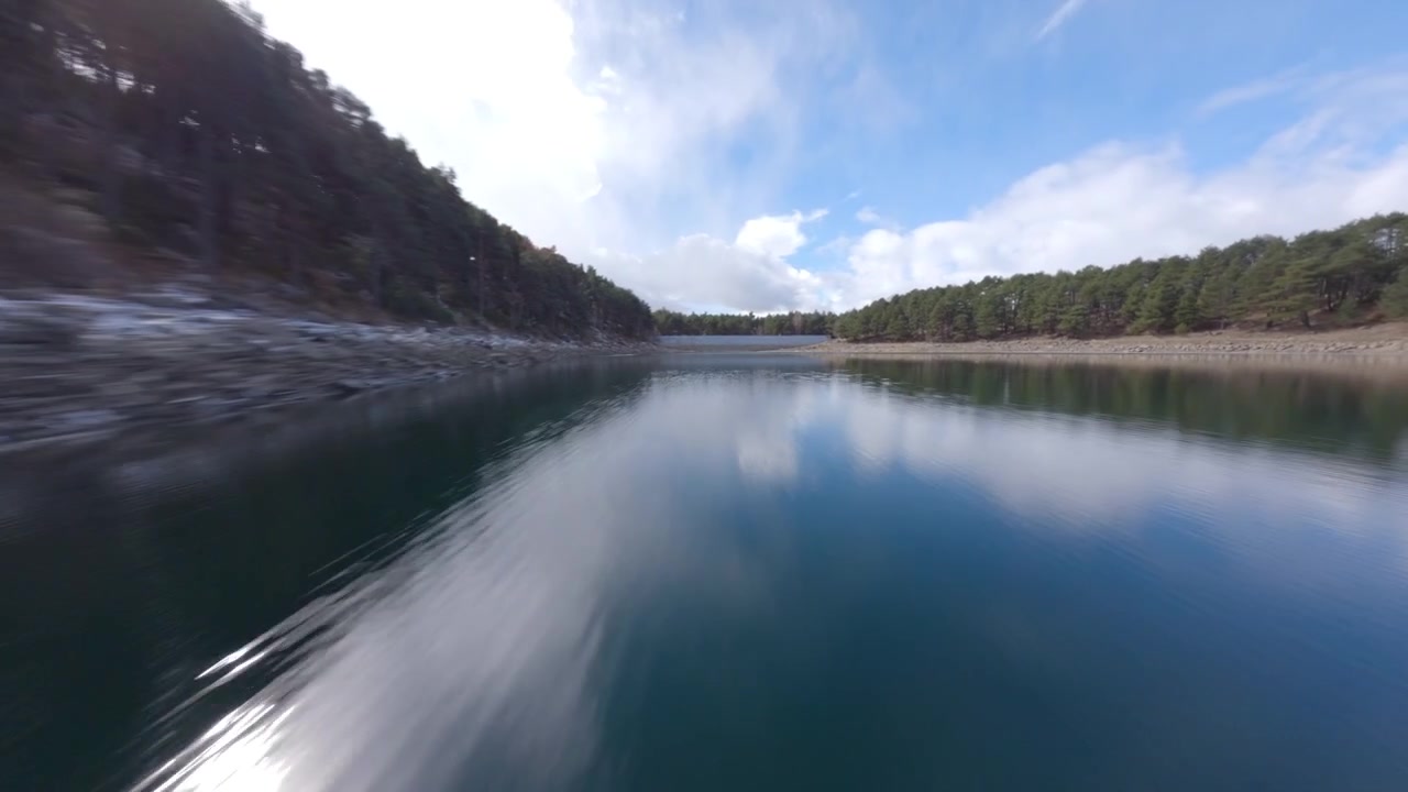 Závodní dron letící v nízké výšce nad jezerem Engolasters, Andorra. Letecký FPV záběr