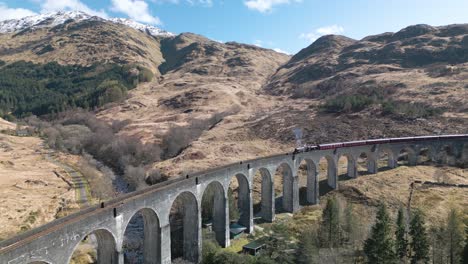 beautiful drone shot of jacobite train crossing glenfinnan viaduct