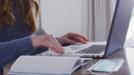 sección media de una mujer limpiando su computadora portátil con un pañuelo