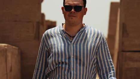 a young man, a tourist, explores the karnak temples in luxor, egypt. walking through the ancient ruins, he enjoys the historic atmosphere of one of the world’s most famous archaeological sites