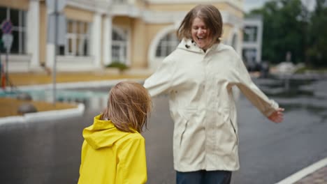 Ein-Vorbeifahrendes-Auto-Schüttet-Wasser-Aus-Einer-Pfütze-Auf-Eine-Blonde-Frau-In-Einer-Weißen-Jacke-Und-Ihre-Teenager-Tochter,-Während-Sie-Im-Park-Spazieren-Gehen