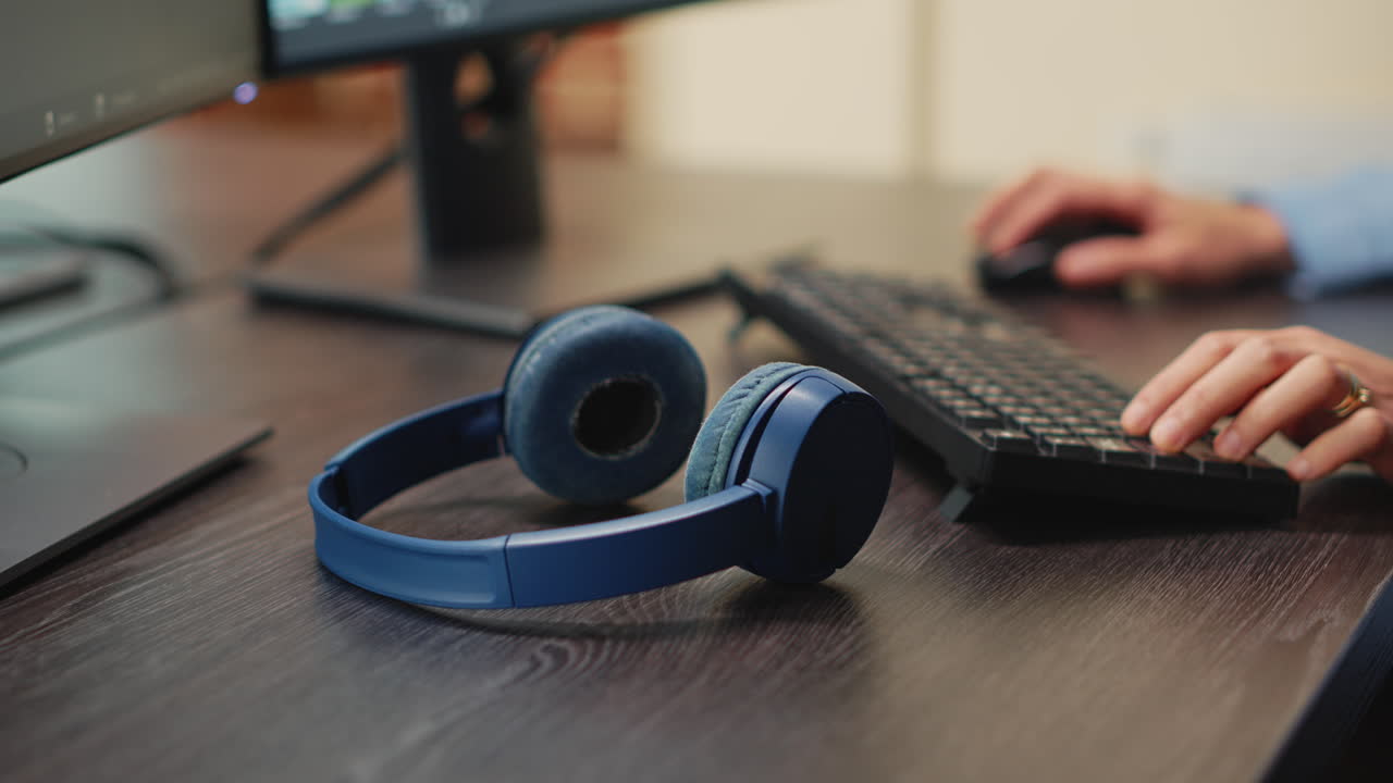 Professional video editor using wireless headphones on desk