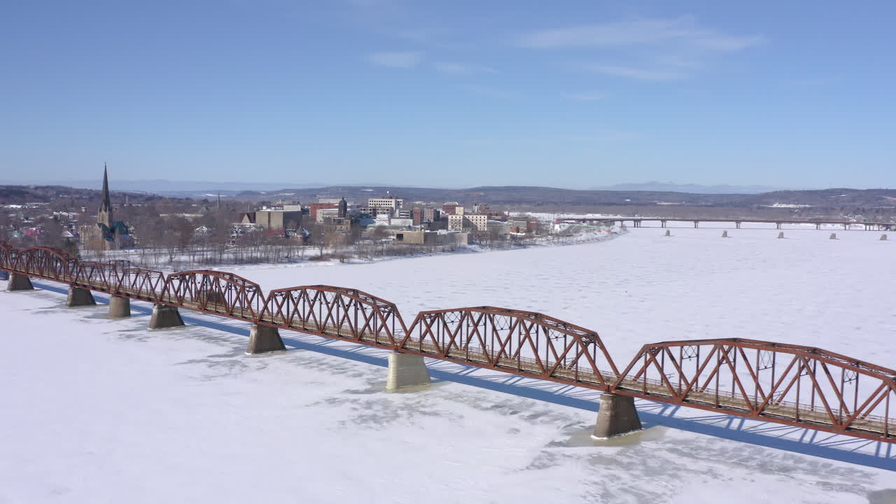 AERIAL: Rotating Around Bill Thorpe Walking Bridge With Fredericton Cityscape In Background