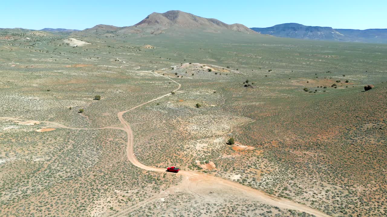 ⁇ 은 트럭이 밝은 초록색과 다채로운 모래로 봄에 네바다 사막을 가로질러 도로를 벗어나고 있는 공중 전망