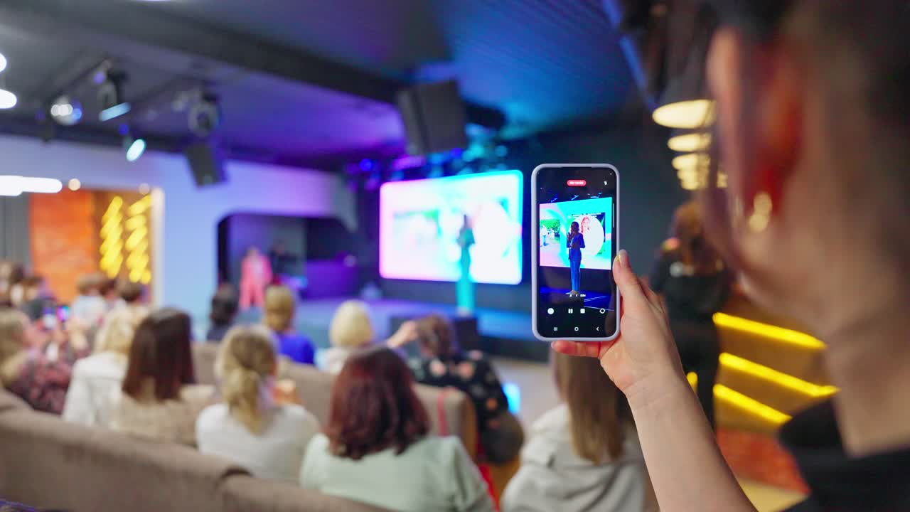 Woman taking a picture of a conference presentation