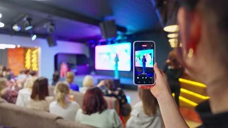 woman taking a picture of a conference presentation