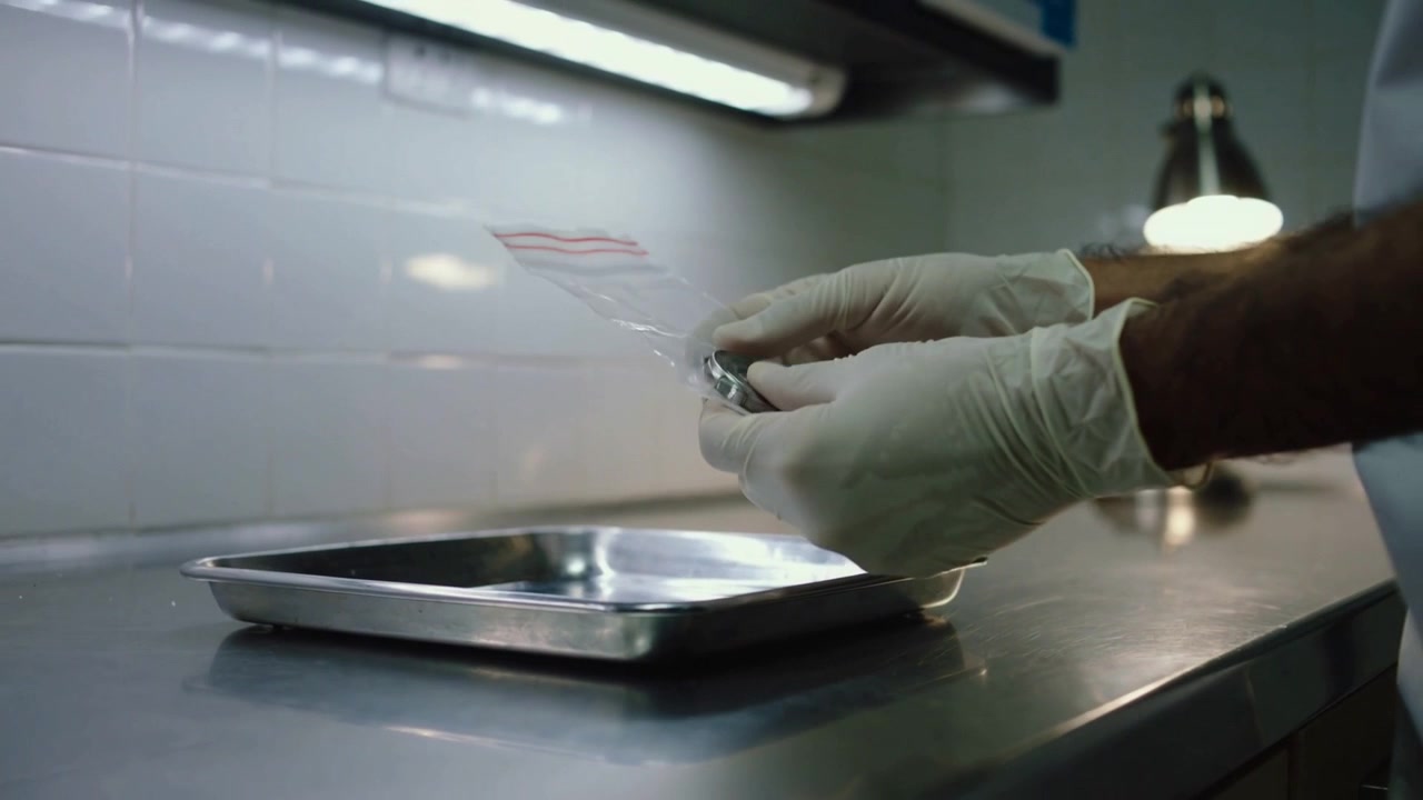 Lifting zip bag, gloved hands placing metal object into bag for storage at clinic, copy space