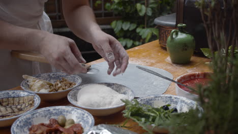 el chef arroja la masa de pizza a la harina de sémola, sobre una mesa de cocina de madera