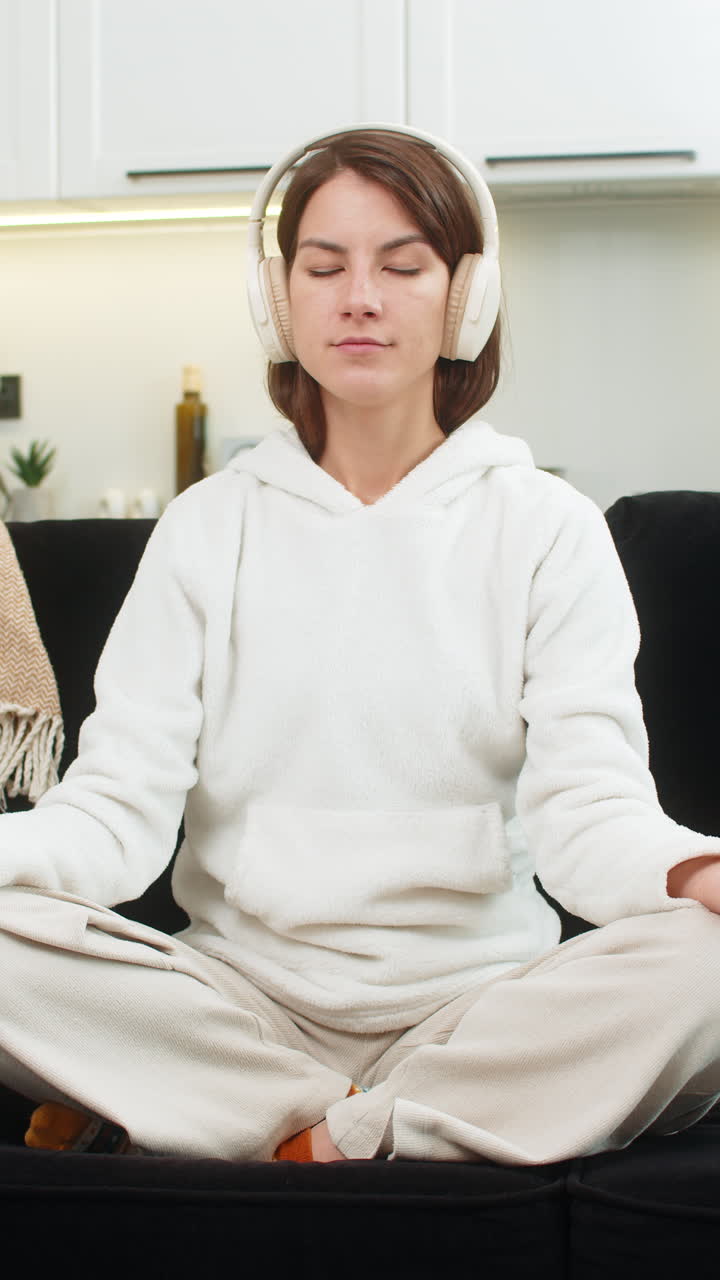 Young woman starts breathing practice meditation on laptop with headphones closes eyes smiles gently