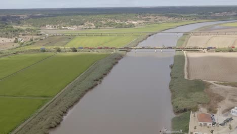 Tren-De-Carga-Cruzando-Un-Puente-De-Acero-Sobre-Un-Campo-De-Arroz