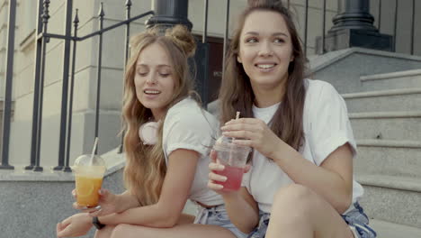 two friends enjoying drinks on steps