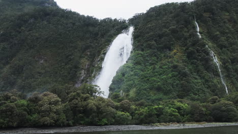 Passing-by-a-massive-waterfall-in-Milford-Sound,-New-Zealand