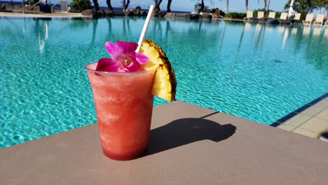 4k-Footage-of-a-Tropical-drink,-with-Pineapple,-on-the-edge-of-a-swimming-pool