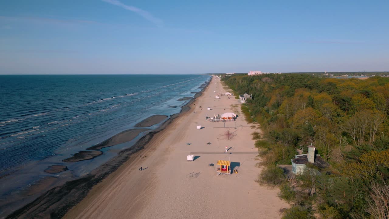 imágenes aéreas de una playa baltica vacía con arena expansiva, bosque exuberante y suaves olas marinas