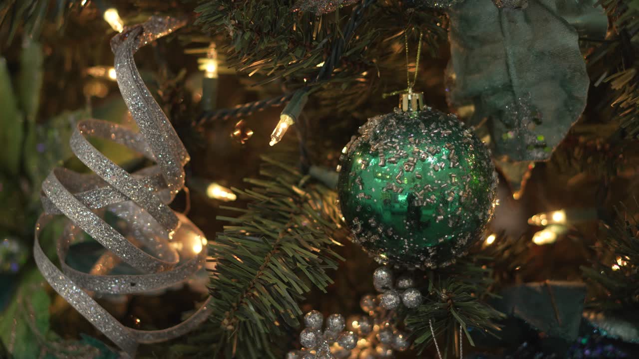 Close-Up of Sparkling Green Christmas Ornaments on a Decorated Tree with Warm Lights. 4k.