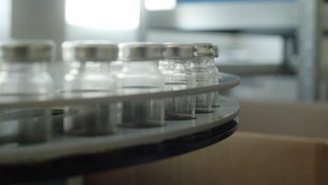 glass vials with a metal cap on a metal carousel in the testing laboratory