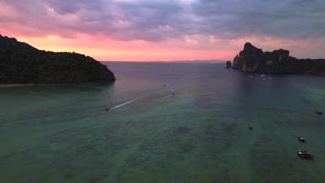 Traditionelle-Thailändische-Longtail-Boote,-Die-Bei-Sonnenuntergang-Auf-Ruhigem-Wasser-Schwimmen,-Mit-Dramatischem-Himmel-Im-Hintergrund,-Panorama-Übersichtsdrohne