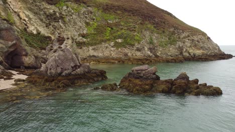 slider shot of rocks pile middle formed in water sea, porth wen beach, united kingdom