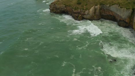 Aérea-De-Arriba-Hacia-Abajo,-Toma-En-órbita-De-Los-Acantilados-A-Lo-Largo-De-La-Costa-En-Nueva-Zelanda-Durante-El-Día