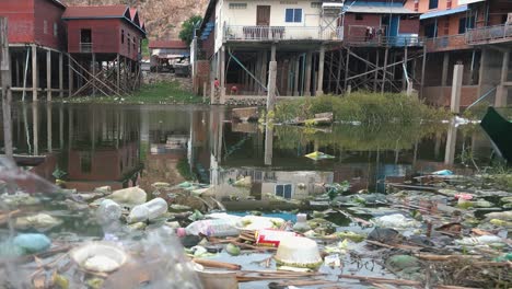 rubbish floating in water next to some stilt house