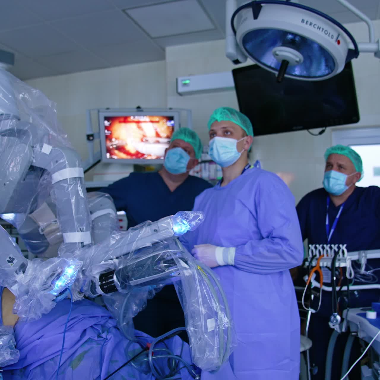 Medical team watching intently the work of Da Vinci robot on the screen. Innovative medical equipment in modern surgery room