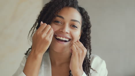 mujer lavándose los dientes con hilo dental