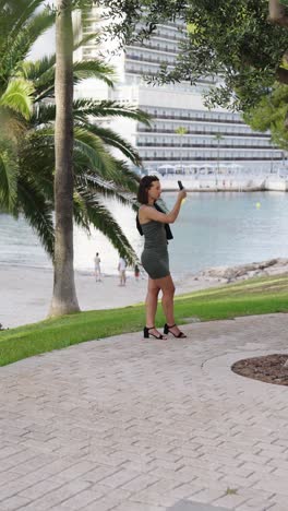 Toma-Vertical-De-Una-Turista-Con-Vestido-Y-Tacones-Altos-Tomando-Fotos,-Mallorca