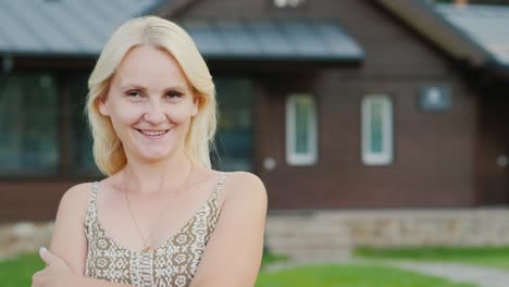 portrait of an attractive woman on the background of her house. looks at the camera, smiling