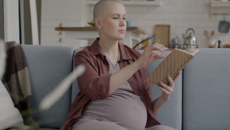 pregnant woman reading a book on the couch