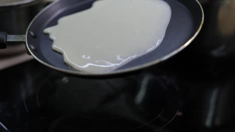 the process of cooking homemade pancakes. woman pours pancake dough on pan