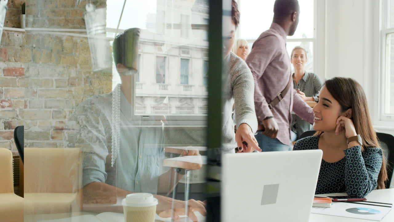 Creative business team meeting in modern start up office female team leader pointing at screen discussing diverse people group teamwork