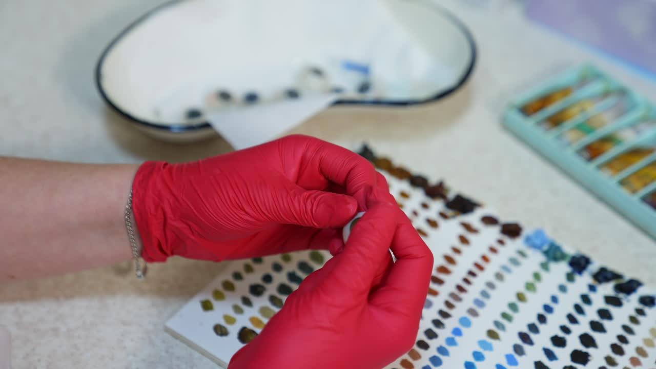 Artificial eye in doctor's hands. Medical specialist in latex gloves holding eye prosthesis on paints background.