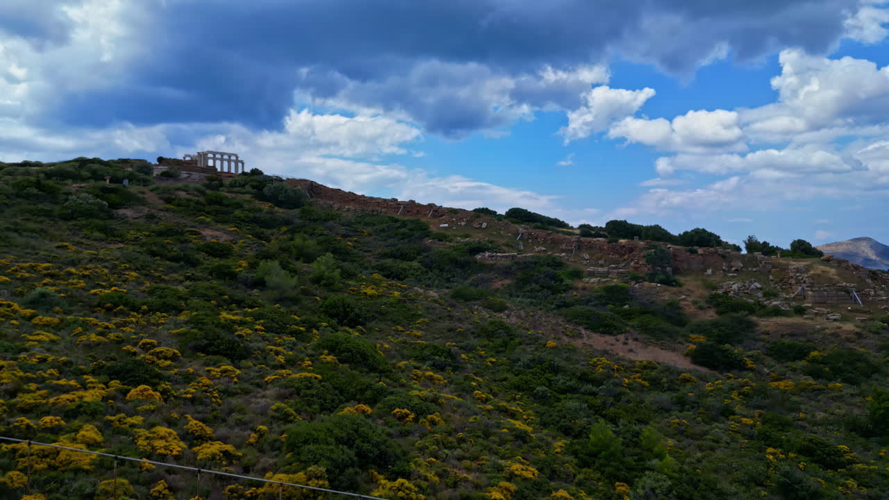 tomada de avión no tripulado del templo de cabo sounion en grecia con algunas nubes, subiendo