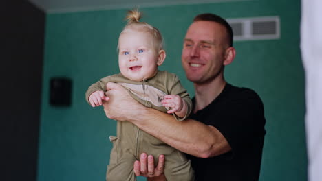 father is waving his cute infant in hands. daddy spending time with his child and plays with him.
