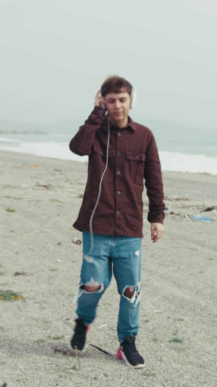 Young Man Listening To Music On A Winter Day At The Beach Near Beach
