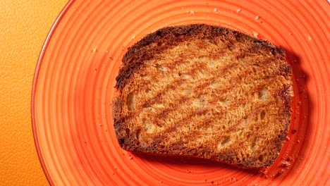 una rebanada de pan tostado en un plato de naranja.