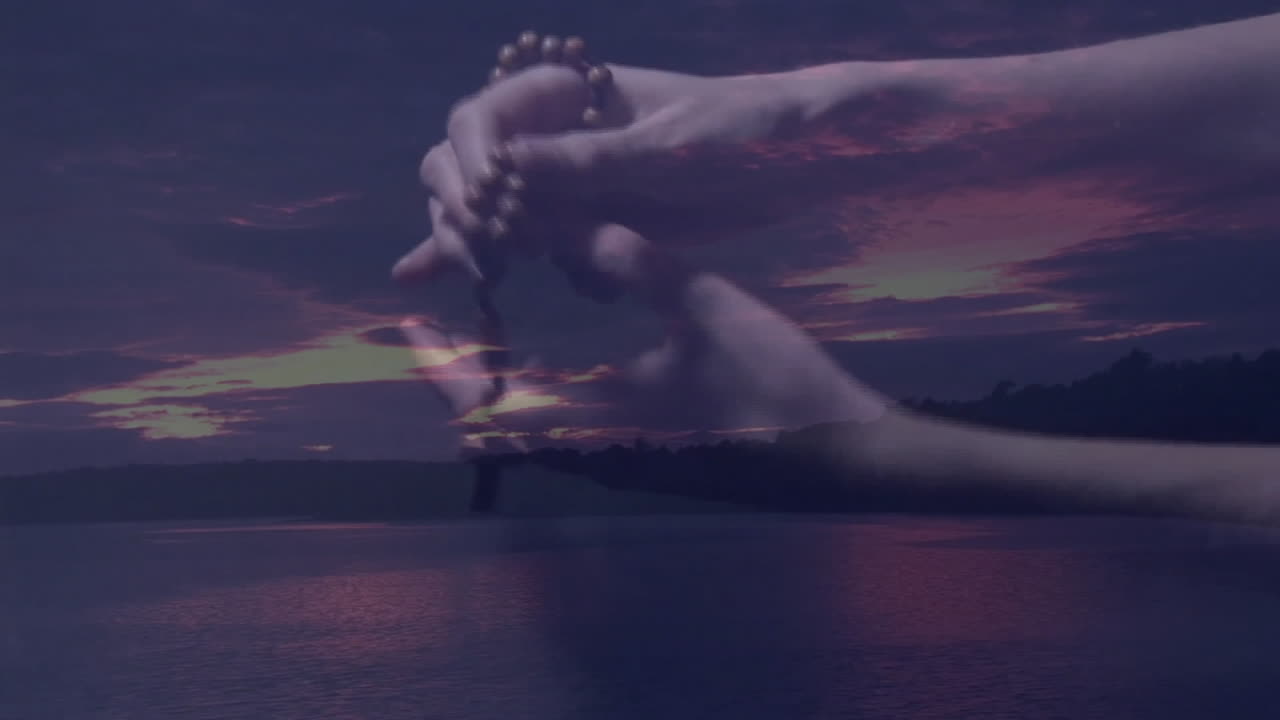 Holding prayer beads, hands reflecting over serene lake during sunset animation