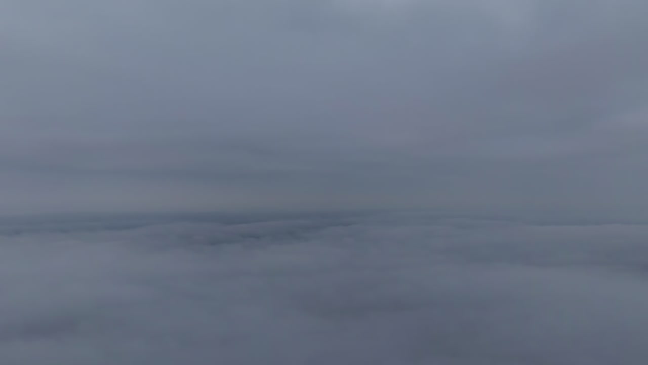 Lapisan awan kelabu rendah yang menggantung padat, lapisan inversi kabut dilihat dari atas