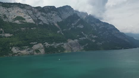 Enorme-Montaña-Rocosa-Con-Vistas-Al-Lago-Verde-Suiza,-Tiro-Estable