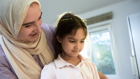 close-up view of mother with hiyab and daughter in the kitchen.
