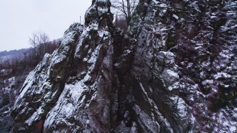 rising view of a snow-covered ferrata in winter with a wooden footbridge, and a view of a mountainous and hilly landscape, czech republic via ferrata vír