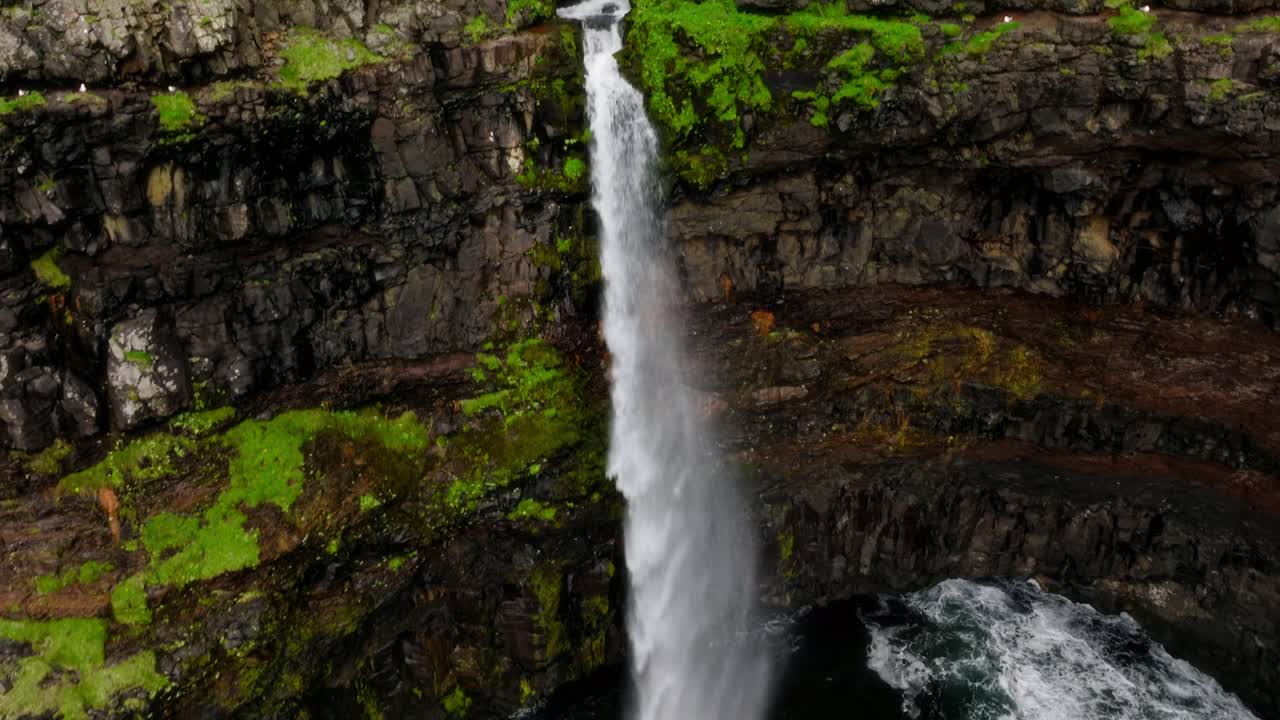 la cascada de múlafossur se sumerge en el mar, enmarcada por exuberantes acantilados, serena pero poderosa