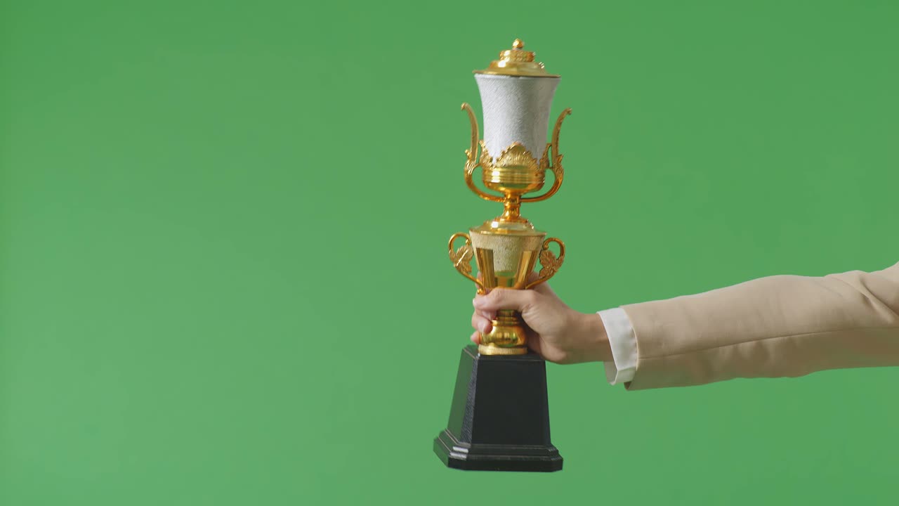 cerca de la mano de la mujer de negocios sosteniendo un trofeo de oro a su lado mostrando el premio ganador como el primer ganador en el fondo de la pantalla verde en el estudio