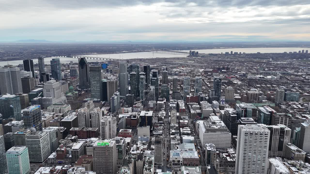 Aerial view of Montreal's snowy cityscape with modern skyscrapers and a bridge over a river on a cloudy day, perfect for business, travel, or lifestyle projects, Canada