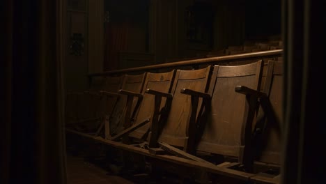 dimly lit rows of abandoned wooden theater seats captured in the shadows, evoking a sense of nostalgia and the passage of time within an empty performance space