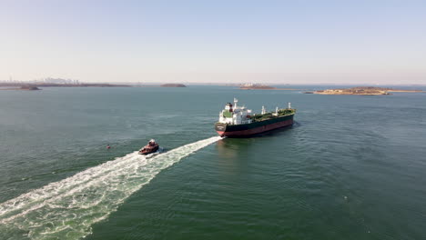 aerial static shot of a tanker on boston harbor, with tugboat following