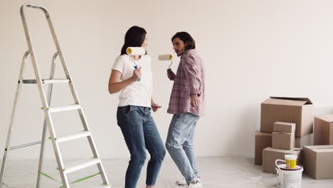 happy couple dancing while painting new home