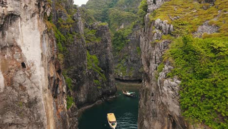 wang long bay escondida detrás de las paredes rocosas enormemente empinadas que están parcialmente cubiertas de vegetación verde mientras un barco navega por la bahía clara